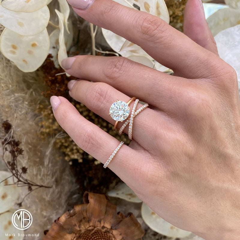 A woman with two rose gold engagement rings touches beautiful flowers.