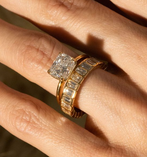 A woman stacks her engagement ring with a custom diamond wedding band.