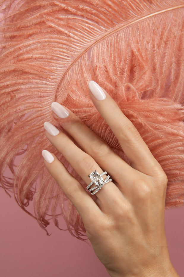 A woman wearing Natural Diamond Rings holds a luxurious pink feather. Natural diamonds are a good investment.