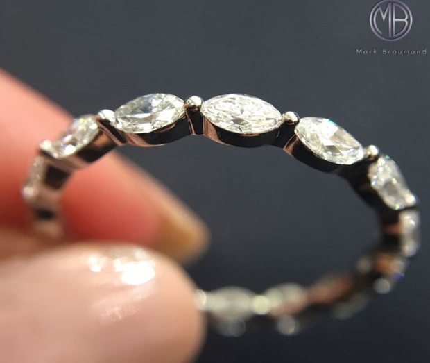 A woman holds a diamond eternity band.