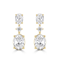A pair of earrings with oval cut diamonds, round cut diamonds and a larger oval cut diamond at the bottom in yellow gold. 