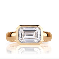 A three carat emerald cut diamond ring set in a bezel with thick band. 