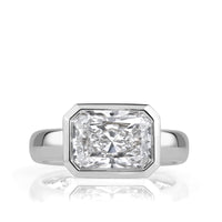 An horizontal radiant cut diamond bezel set in white gold with a thick band. 