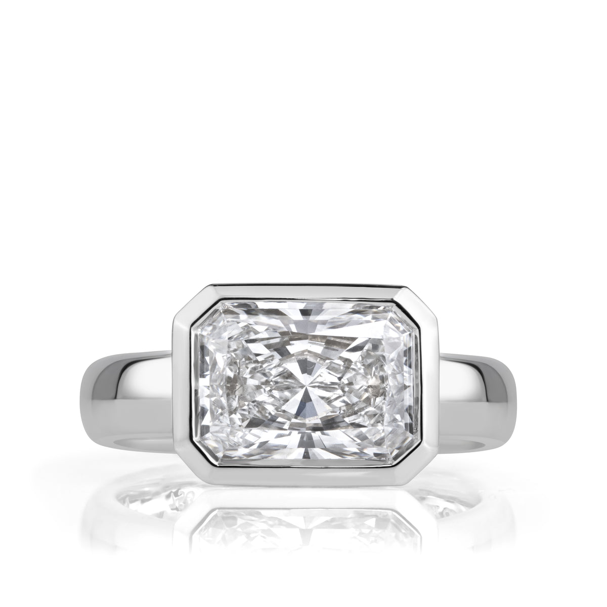 An horizontal radiant cut diamond bezel set in white gold with a thick band. 
