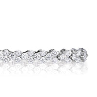 Detailed shot of round brilliant cut diamond tennis bracelet showing how each diamond is set with three prongs clustered in sets of three. 