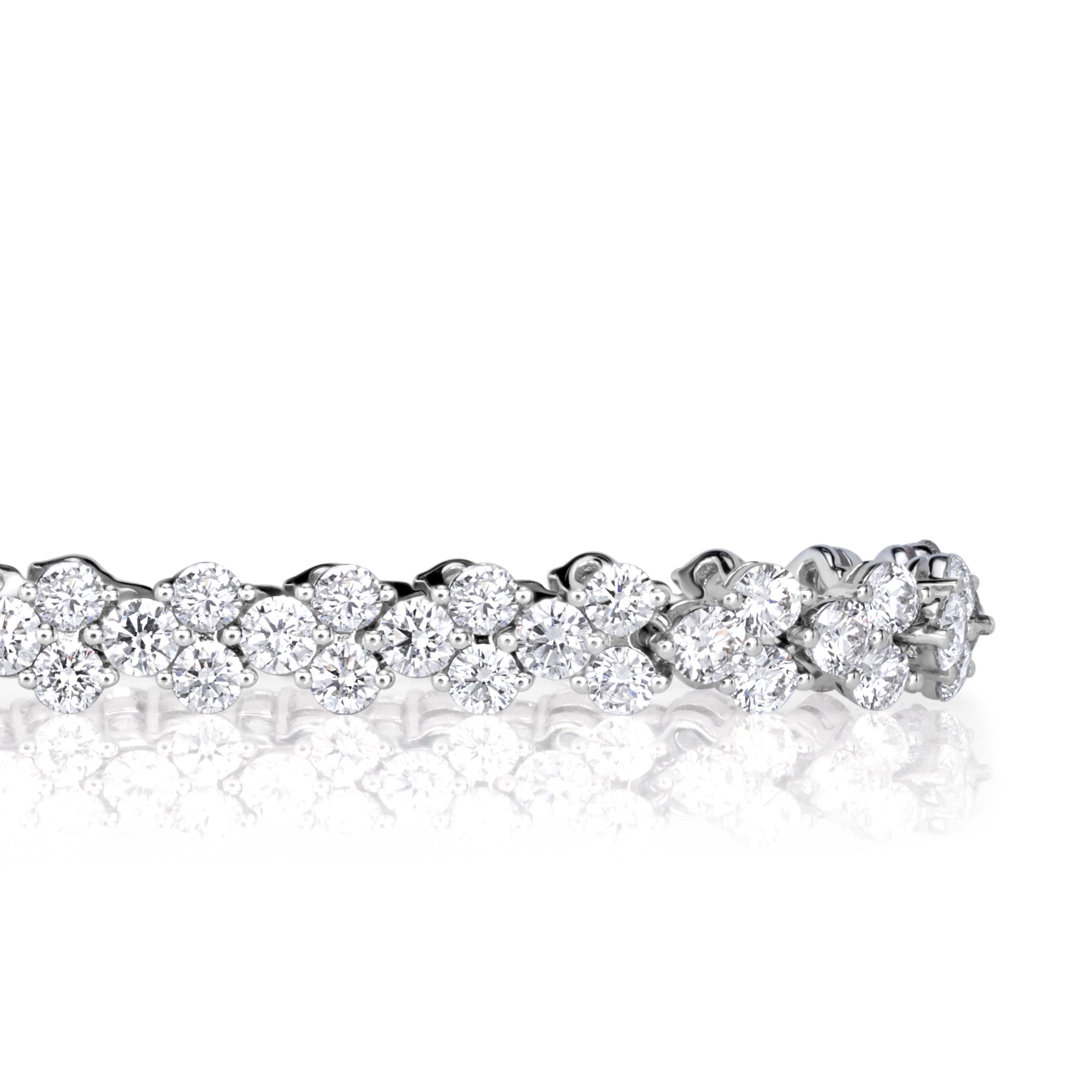 Detailed shot of round brilliant cut diamond tennis bracelet showing how each diamond is set with three prongs clustered in sets of three. 