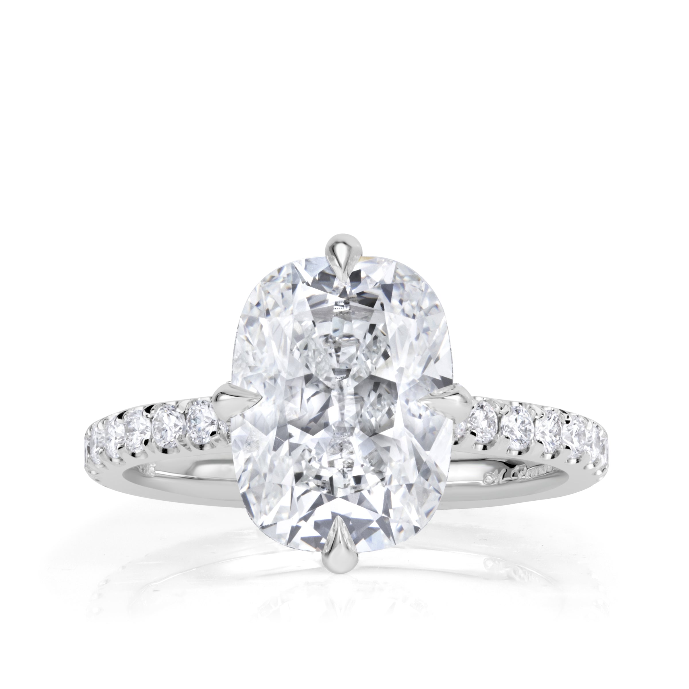 Platinum engagement ring with an elongated old mine cut diamond set with 4 prongs in a compass style, pave diamond band and hidden halo of diamonds under the center stone. 