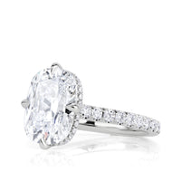 Side view of Platinum engagement ring with an elongated old mine cut diamond set with 4 prongs in a compass style, pave diamond band and hidden halo of diamonds under the center stone. 