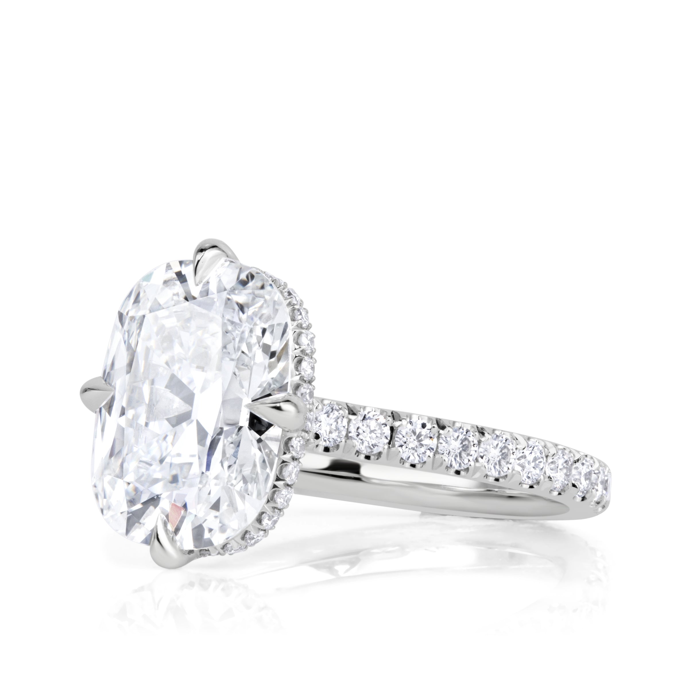 Side view of Platinum engagement ring with an elongated old mine cut diamond set with 4 prongs in a compass style, pave diamond band and hidden halo of diamonds under the center stone. 