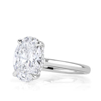 Oval diamond engagement ring on platinum band with hidden halo and pave diamonds on the shank under the diamond. 