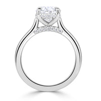 Oval diamond engagement ring on platinum band with hidden halo and pave diamonds on the shank under the diamond. 