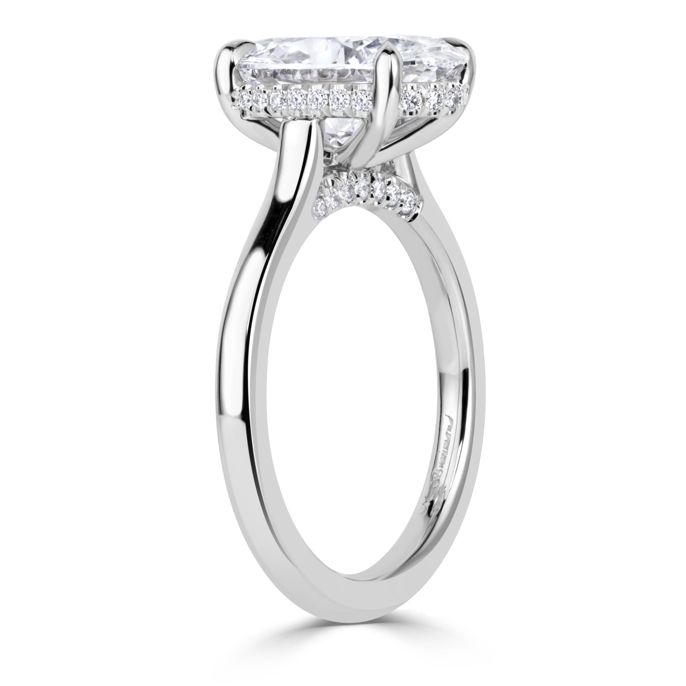 Oval diamond engagement ring on platinum band with hidden halo and pave diamonds on the bridge of the band under the center diamond. 